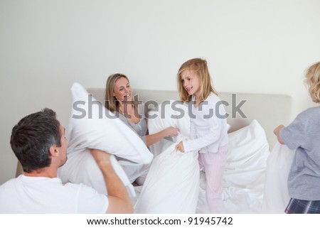 Family having a pillow fight together in the bedroom