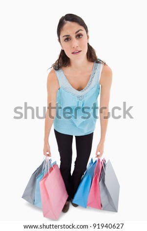 Portrait of a tired woman posing with shopping bags against a white background