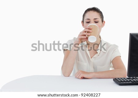 Businesswoman drinking a takeaway tea while using a computer against a white background