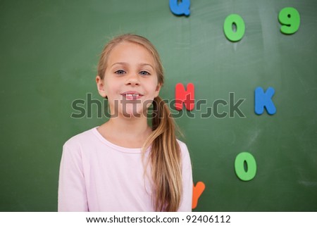 Schoolgirl posing in front of a blackboard in a classroom
