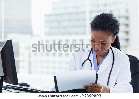 Female doctor signing a document in her office