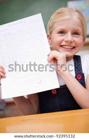 Portrait of a girl showing her school report in a classroom