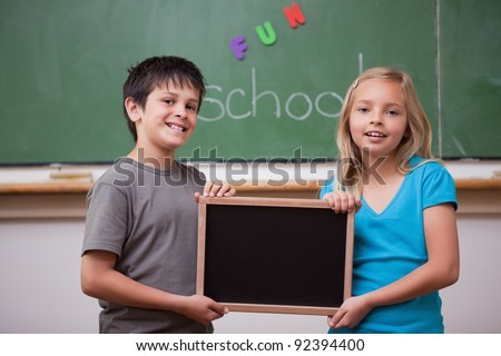 Smiling pupils holding a school slate in a classroom