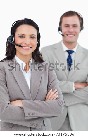 Smiling call center agents with headsets and arms folded against a white background