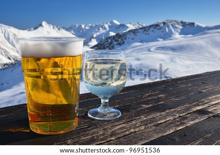 Glasses with beer and white wine on a wooden table in high mountain cafe. Shallow depth of field.