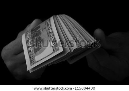 man holding dollars stack on black background