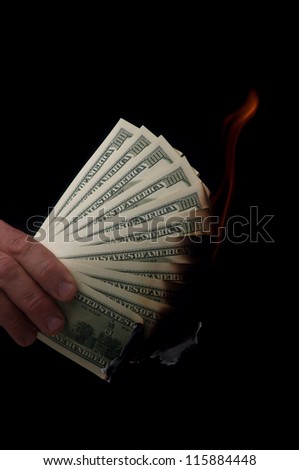 man holding stack of dollars and match fire
