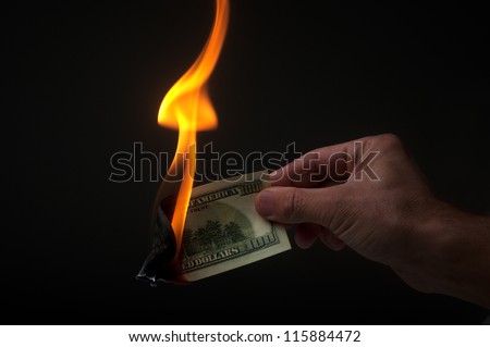 man burns money on black background