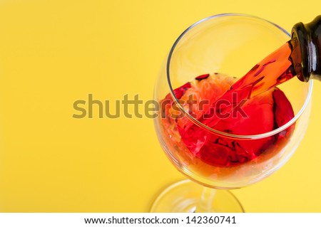 Pouring red wine into a glass on a yellow background