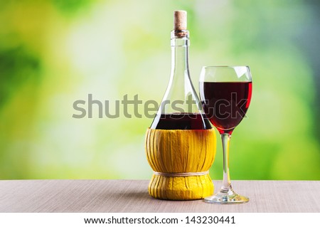 Glass of wine and bottle on natural background