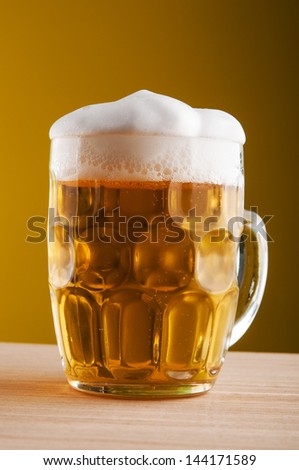 Mug of beer on yellow background