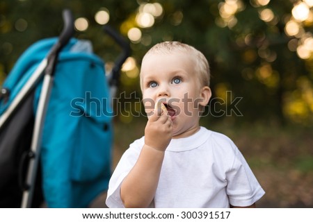 Boy playing outside and eat cookie at green park background