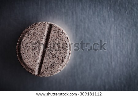 close up of one pill on dark background