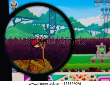 LISBON - JANUARY 29, 2014: Photo of Angry Birds game on a monitor screen through a magnifying glass.