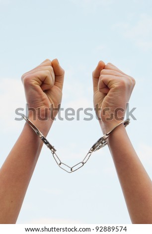 stock photo Handcuffed woman's hands against blue sky
