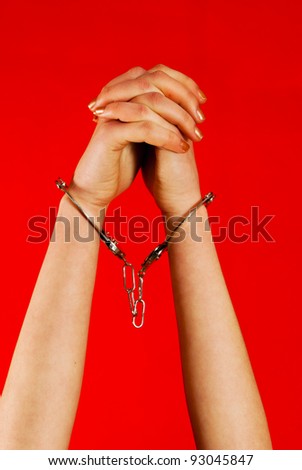 stock photo Handcuffed woman's hands against red background
