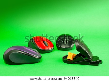 Three computer mouses with a mousetrap over green background