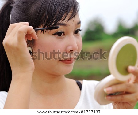 Asian woman making up her face