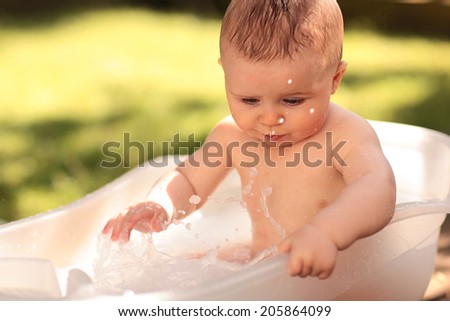 Happy Baby Boy Splashing in the Water Outside in Hot Weather