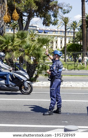 NICE, FRANCE - MAY 18, 2014: Municipal Policeman directs traffic in the city, Municipal Police are one of the three components of French policing, alongside the National Police and the Gendarmerie