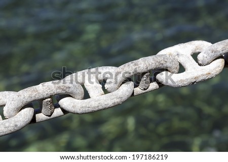 Galvanized chain mooring line being shown on the background color of the sea