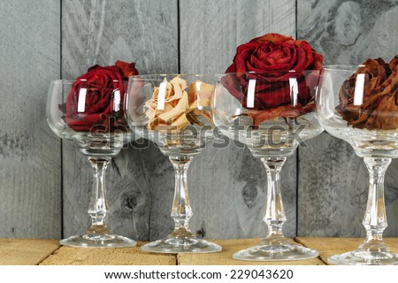 Glasses with roses symbolize wine, shown on the background of stained plank