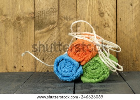 Three towels rolled up and tied with string shown on the background of stained wood