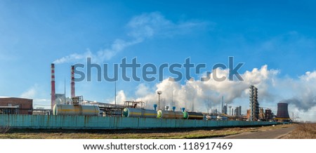 Panorama of the chemical factory throwing out polluting smoke from pipes in the blue sky