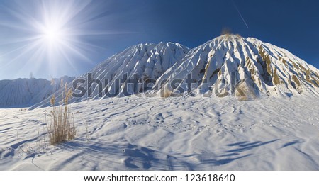 Landscape with waste heap in snow and plane flying by in the sky, winter outdoor