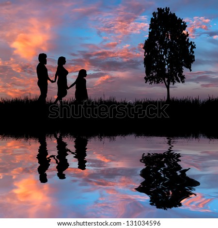 Happy family walking on the lake coast on a background of the majestic sunset