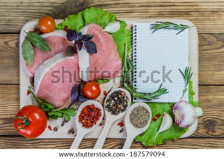 Raw pork meat and spices on rustic table with paper for recipe
