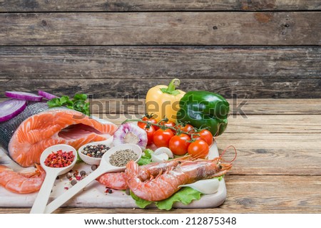 Fish filets and shrimps on rustic table with spices