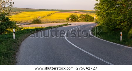 A winding road with tire tracks on the asphalt, a sharp turn