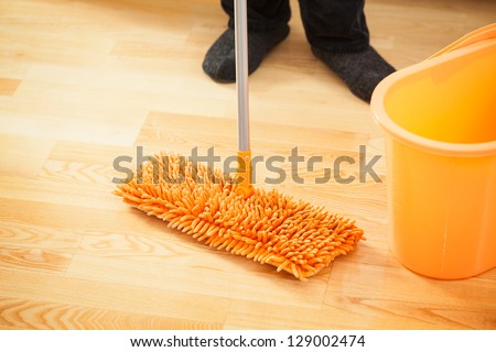 Close up of orange mop and bucket on the floor