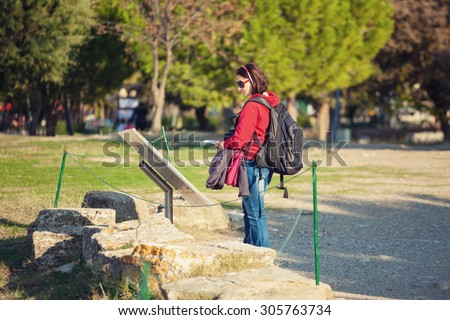 Female tourist with audio guide, reading text on board in front of ruins in Troy, Turkey