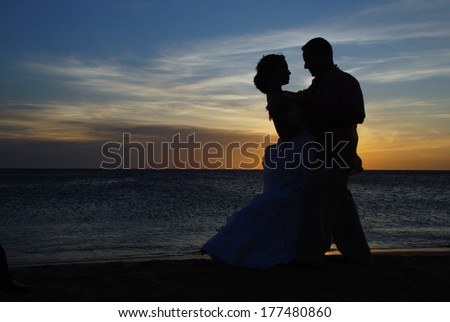 Romantic silhouette of a wedding couple dancing on the beach at sunset