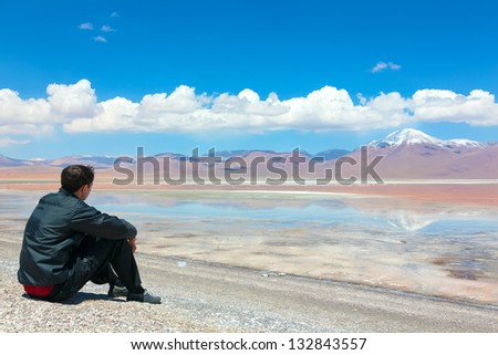 Young man sitting alone on the shore of Laguna Colorada, Bolivia