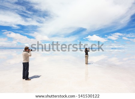 Man photographs woman who takes pictures of lake Salar de Uyuni, Bolivia