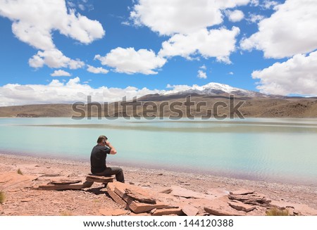 Man sitting on the shore of lagoon Celeste and talking on phone