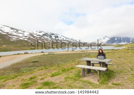 Woman working on laptop among the mountains
