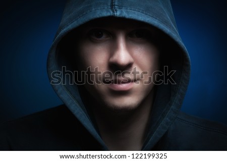 Scary evil man with hood in darkness