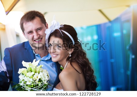 bride and groom is laughing near the glass modern building