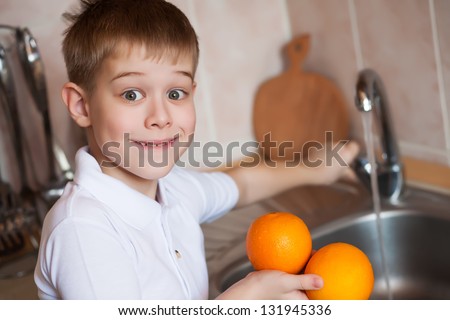 kid is washing fruit in the kitchen