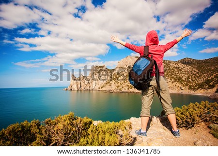 young woman tourist is enjoying landscape with outstretched arms