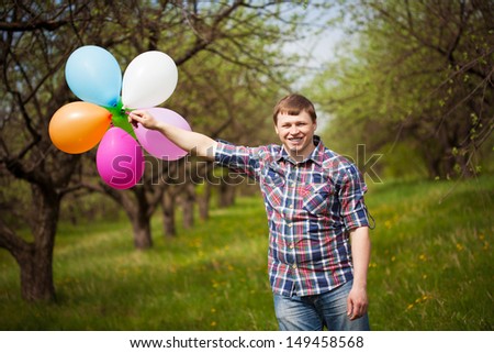 man with balloons on the green meadow
