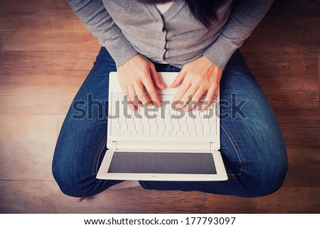 woman is sitting on wood floor with laptop