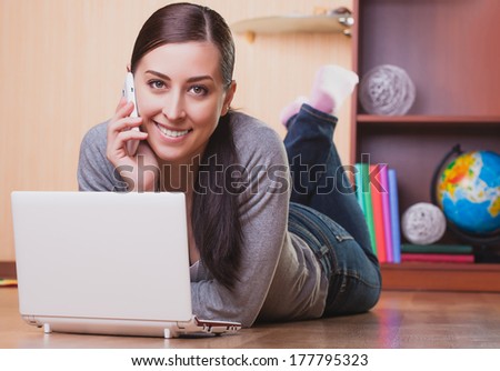smiling young woman lying on wood floor with laptop