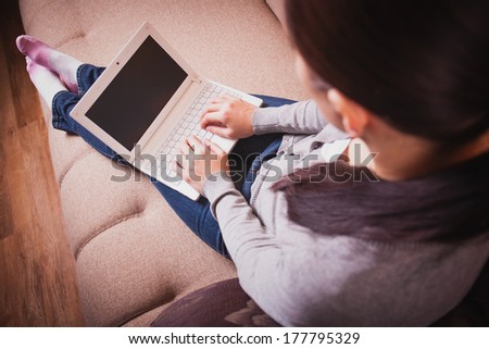 woman is sitting on the couch with laptop