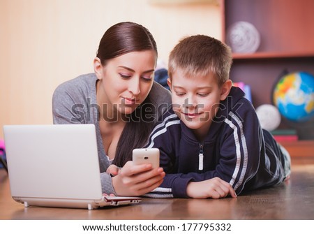 mom and son are lying on wood flooring with laptop