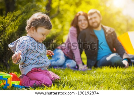 mother and father are playing with their daughter in the park